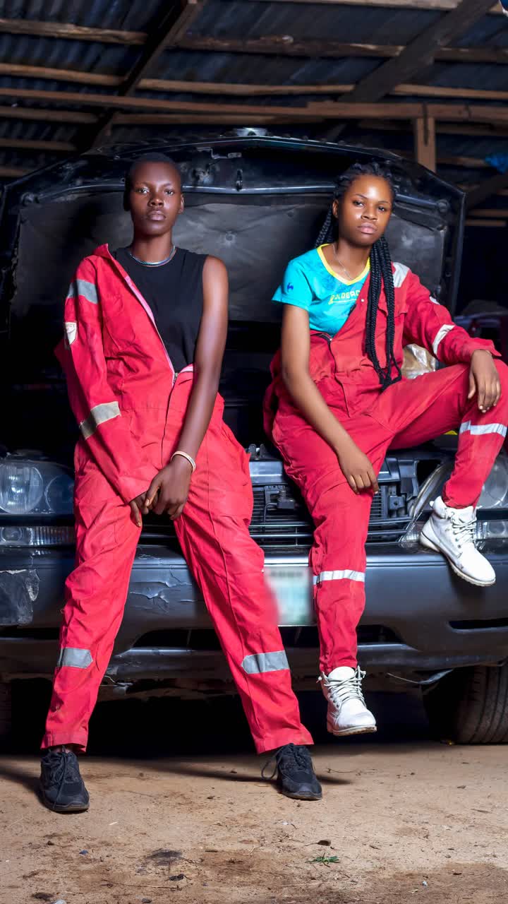 Two mechanics in red overalls in front of an open bonnet